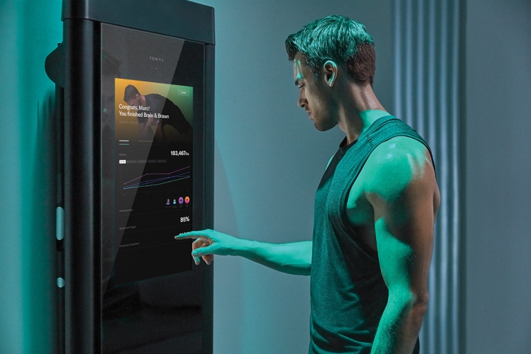 Man in workout clothes reviewing a Tonal workout summary