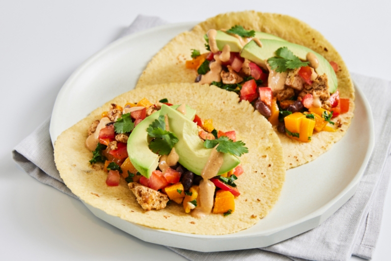 a plate with two tacos topped with avocados